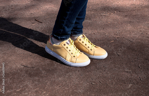 Yellow sneakers decorated with daisies in the park