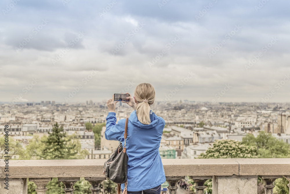 Woman tourist taking photo of the city in cloudy weather