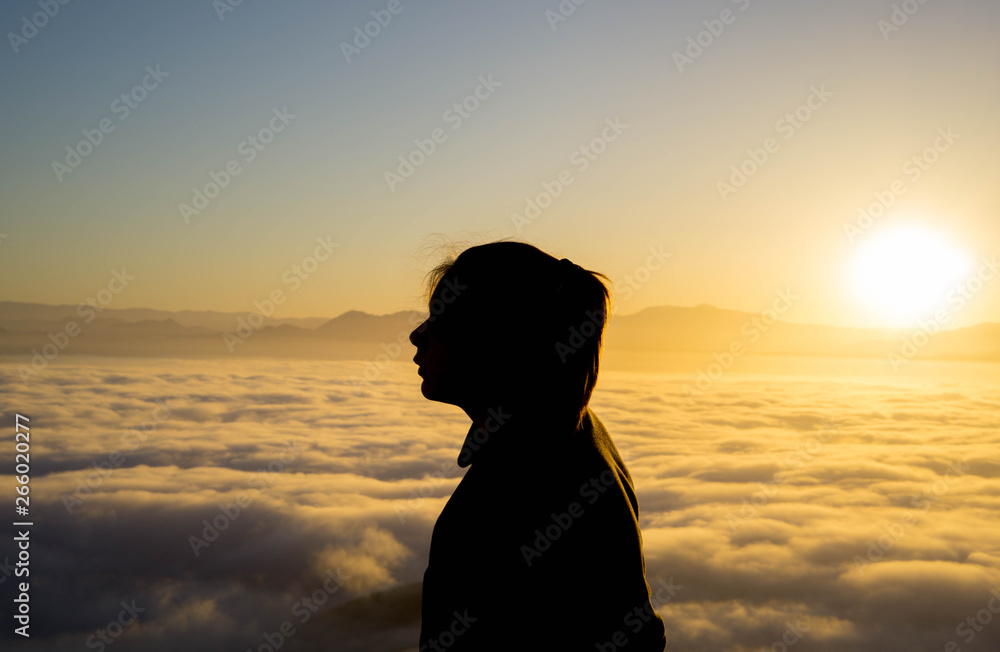 silhoutette of a young woman in the mountains during sunrise