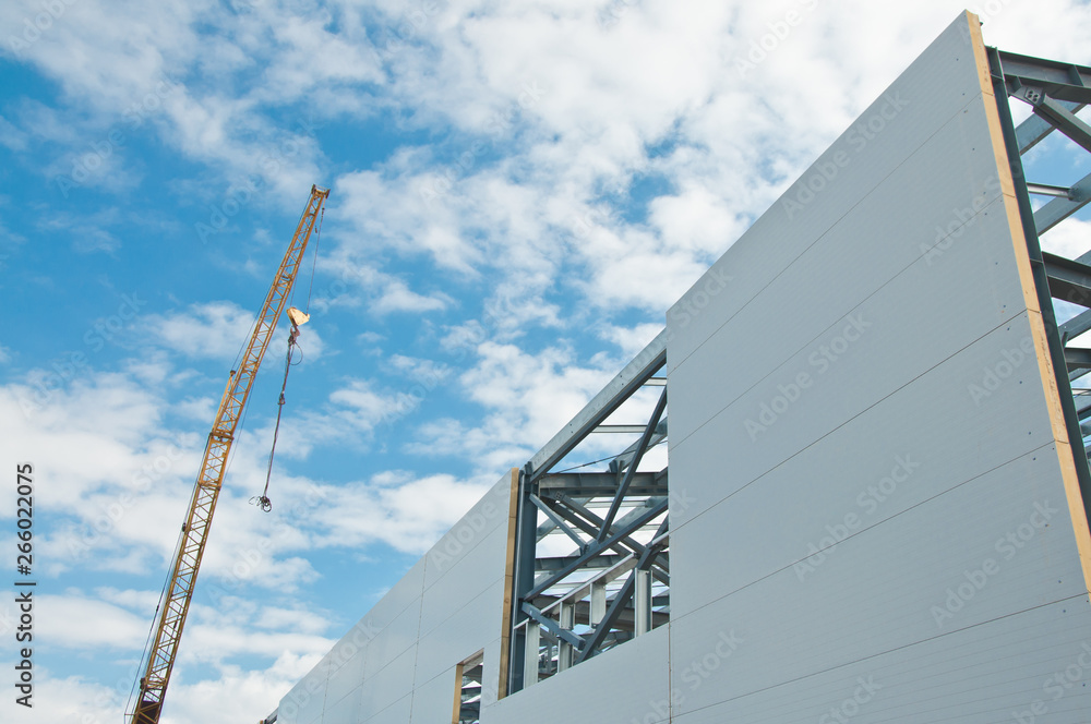 Metal frame of the building with a sandwich panel of insulation on the wall. Construction of a new industrial building. Metal frame of the building with a sandwich panel of insulation on the wall. Construction of a new industrial building.