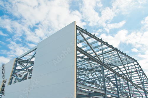 Metal frame of the building with a sandwich panel of insulation on the wall. Construction of a new industrial building.