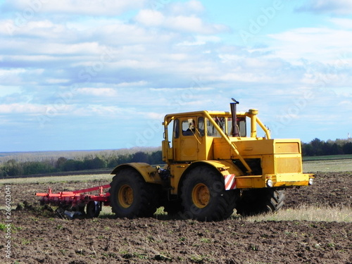 Tractor plows field. Tractor rides on the field and plows arable land.  Details and close-up. © Dmitry