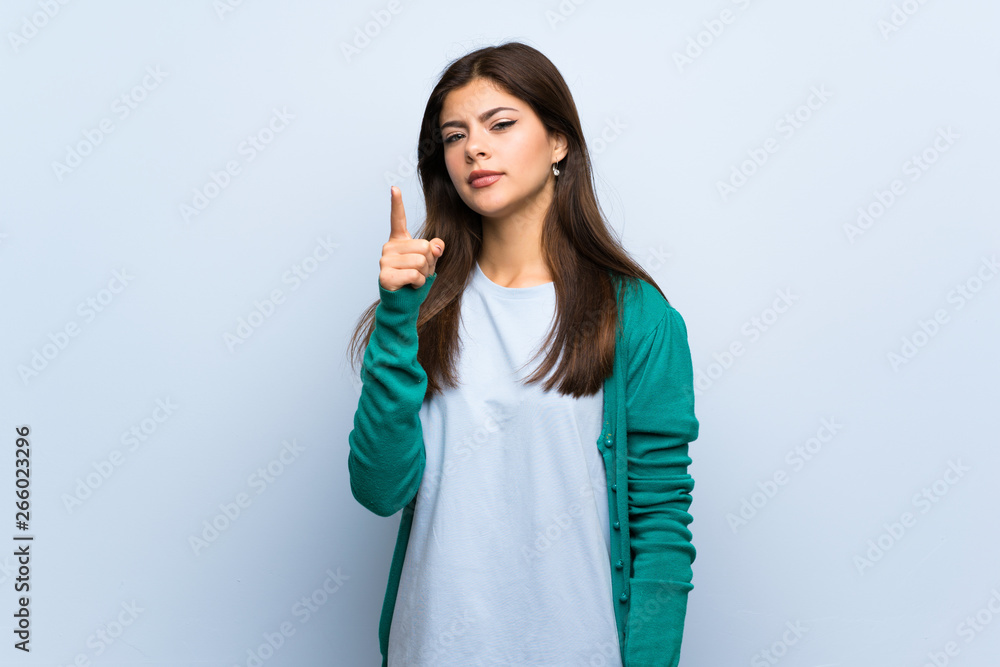Teenager girl over blue wall frustrated and pointing to the front Teenager girl over blue wall frustrated and pointing to the front