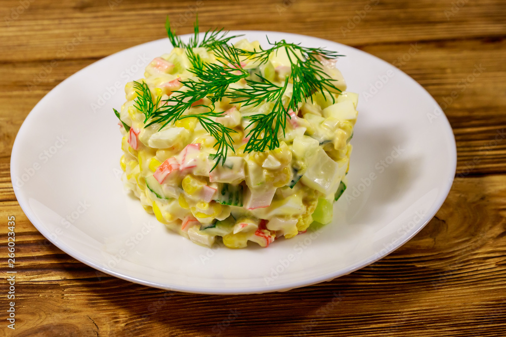 Salad with crab sticks, sweet corn, cucumber, eggs and mayonnaise on wooden table Salad with crab sticks, sweet corn, cucumber, eggs and mayonnaise on wooden table