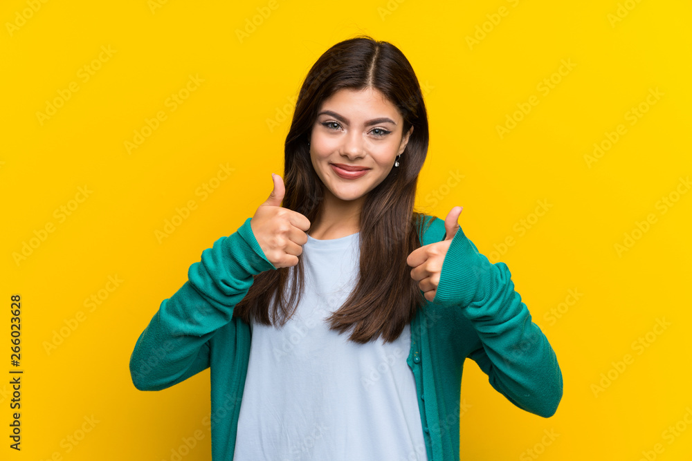 Teenager girl over yellow wall giving a thumbs up gesture Teenager girl over yellow wall giving a thumbs up gesture