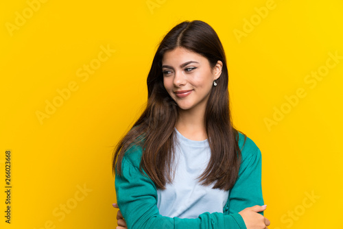 Fotografia Teenager girl over yellow wall standing and looking to the side