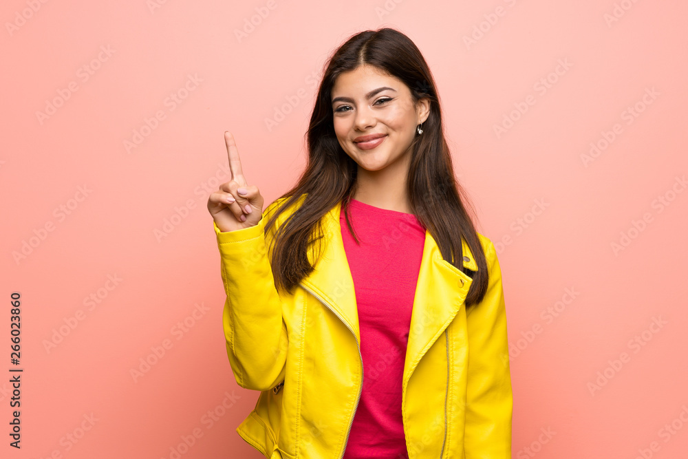 Teenager girl over pink wall showing and lifting a finger in sign of the best Teenager girl over pink wall showing and lifting a finger in sign of the best