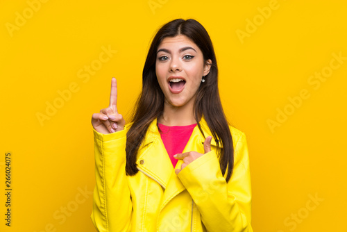 Teenager girl over yellow wall with surprise facial expression