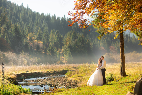 Wedding couple near the river in the Carpathians mountains in sunny day