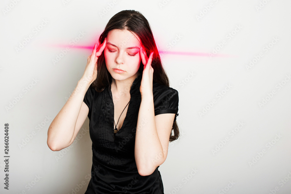young woman is suffering from a headache. Portrait of a girl clutching her head. Migraines and blood pressure problems young woman is suffering from a headache. Portrait of a girl clutching her head. Migraines and blood pressure problems