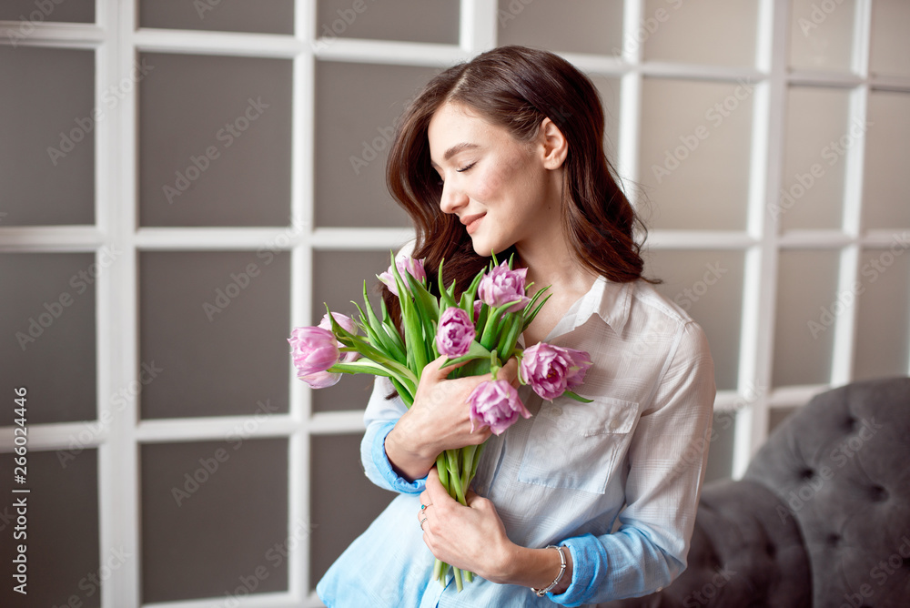 Young beautiful brunette girl holding a spring bouquet of tulips in her hands. Lifestyle Young beautiful brunette girl holding a spring bouquet of tulips in her hands. Lifestyle