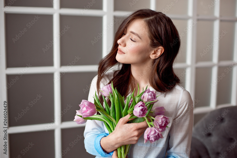 Young beautiful brunette girl holding a spring bouquet of tulips in her hands. Lifestyle Young beautiful brunette girl holding a spring bouquet of tulips in her hands. Lifestyle