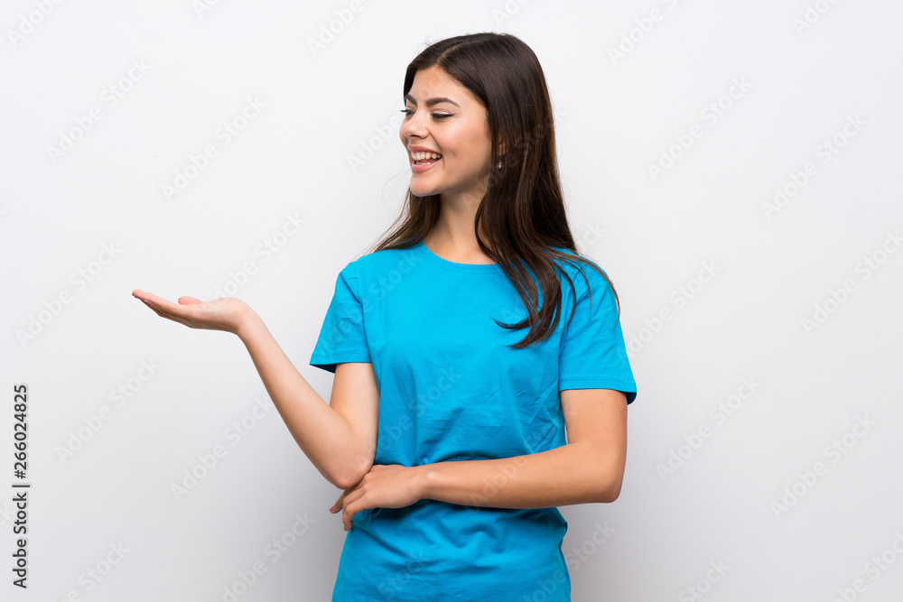 Teenager girl with blue shirt holding copyspace imaginary on the palm to insert an ad Teenager girl with blue shirt holding copyspace imaginary on the palm to insert an ad