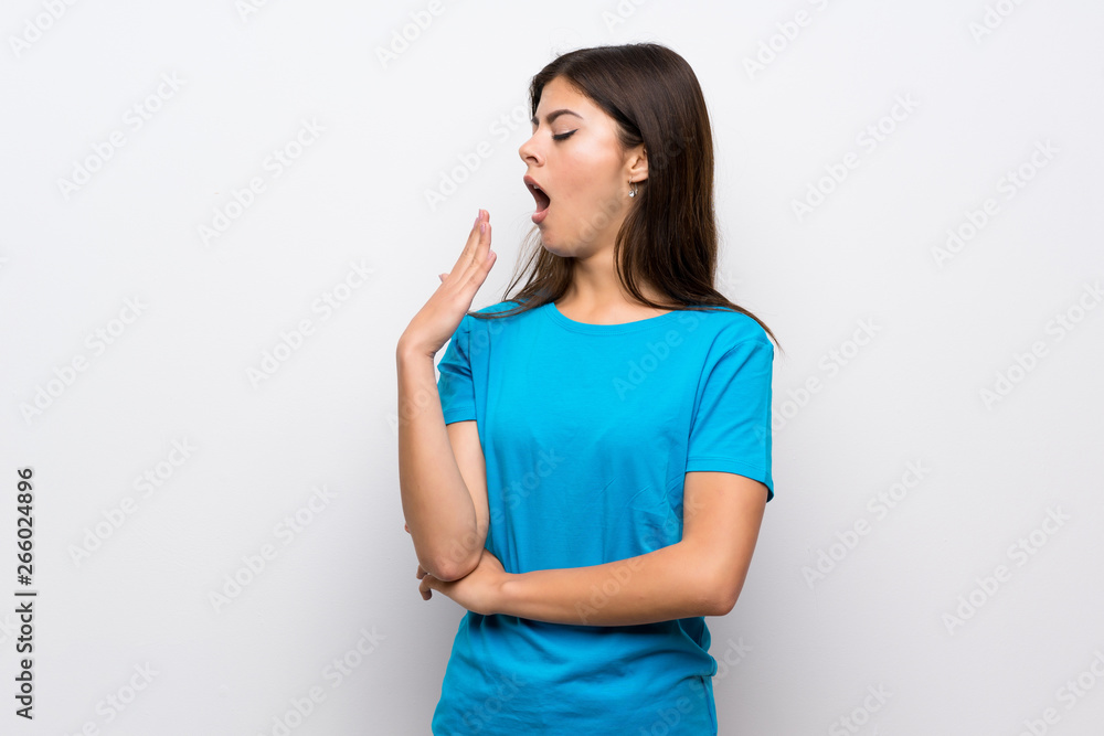 Teenager girl with blue shirt yawning and covering wide open mouth with hand Teenager girl with blue shirt yawning and covering wide open mouth with hand