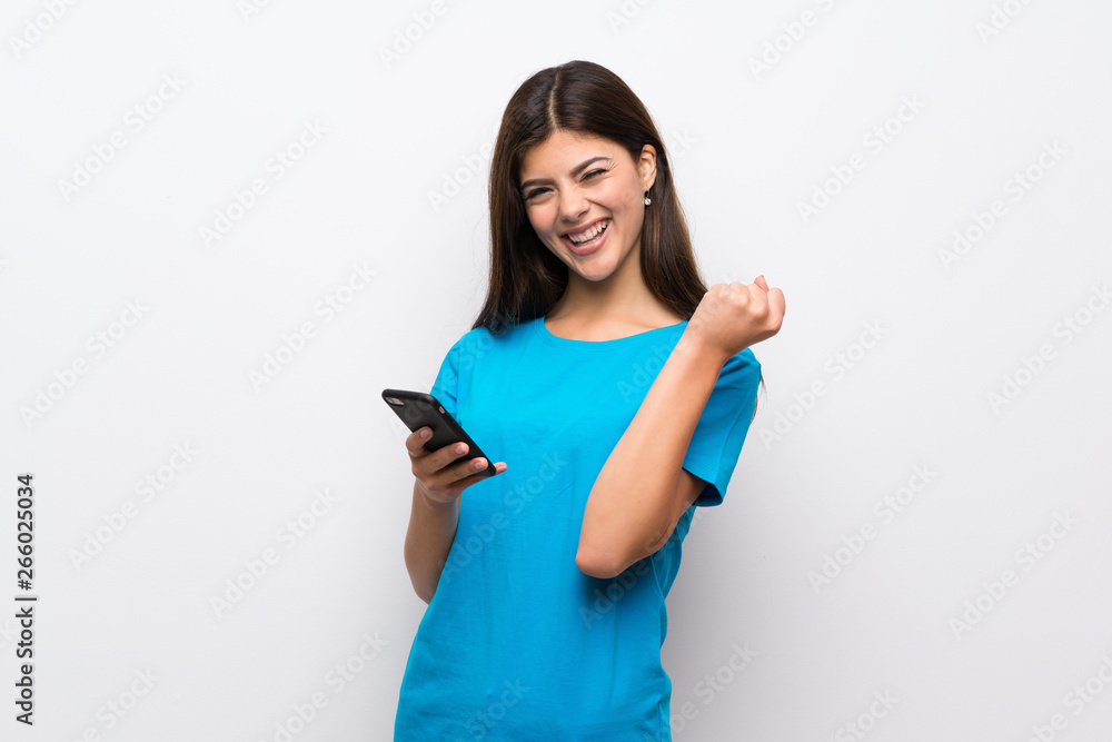 Teenager girl with blue shirt with phone in victory position Teenager girl with blue shirt with phone in victory position