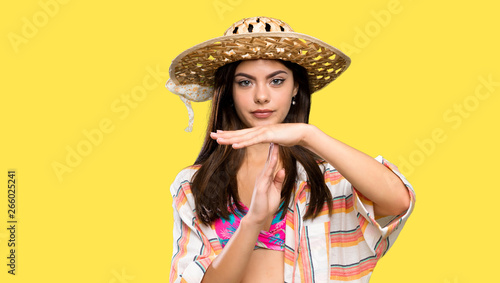 Teenager girl on summer vacation making time out gesture over isolated yellow background