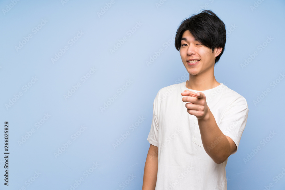 Asian man on isolated blue background points finger at you Asian man on isolated blue background points finger at you