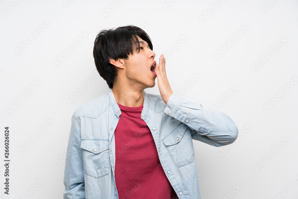 Asian man on isolated white background yawning and covering wide open mouth with hand Asian man on isolated white background yawning and covering wide open mouth with hand