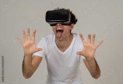 Portrait of cheerful and shocked young man wearing Virtual Reality headset exploring 3D world