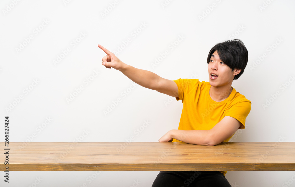 Asian man with yellow shirt pointing away Asian man with yellow shirt pointing away