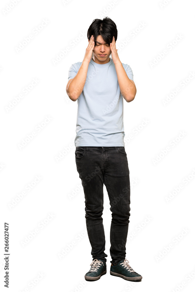 A full-length shot of a Asian man with blue shirt with headache over isolated white background A full-length shot of a Asian man with blue shirt with headache over isolated white background