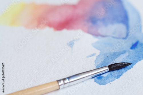 Close-up of beautiful watercolor brushstrokes on a white sheet, a brush in the picture