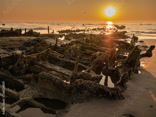 Tableau sur toile Wreckage of a world war ship at sunset close to the beach