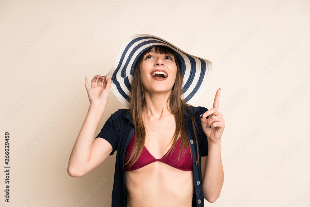 Woman in bikini on ocher background pointing with the index finger a great idea Woman in bikini on ocher background pointing with the index finger a great idea