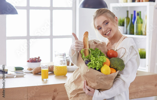 Young woman holding grocery shopping bag with vegetables Standi