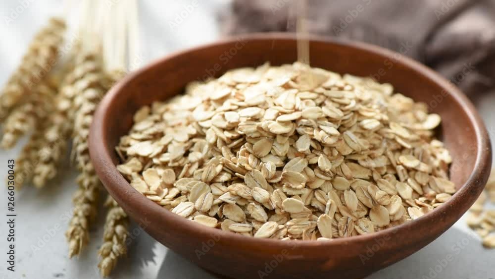 Slow motion of oats or oat flakes falling into bowl. Healthy food, healthy eating, agriculture harvest concept Slow motion of oats or oat flakes falling into bowl. Healthy food, healthy eating, agriculture harvest concept