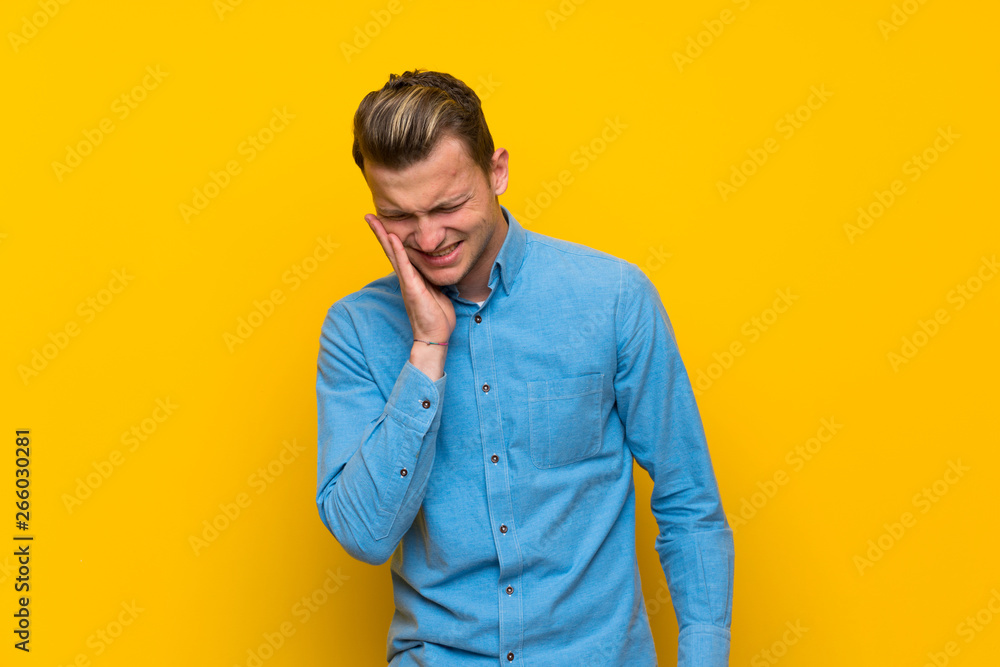 Blonde man over isolated yellow wall with toothache Blonde man over isolated yellow wall with toothache
