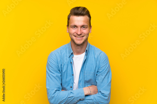 Blonde handsome man over isolated wall laughing