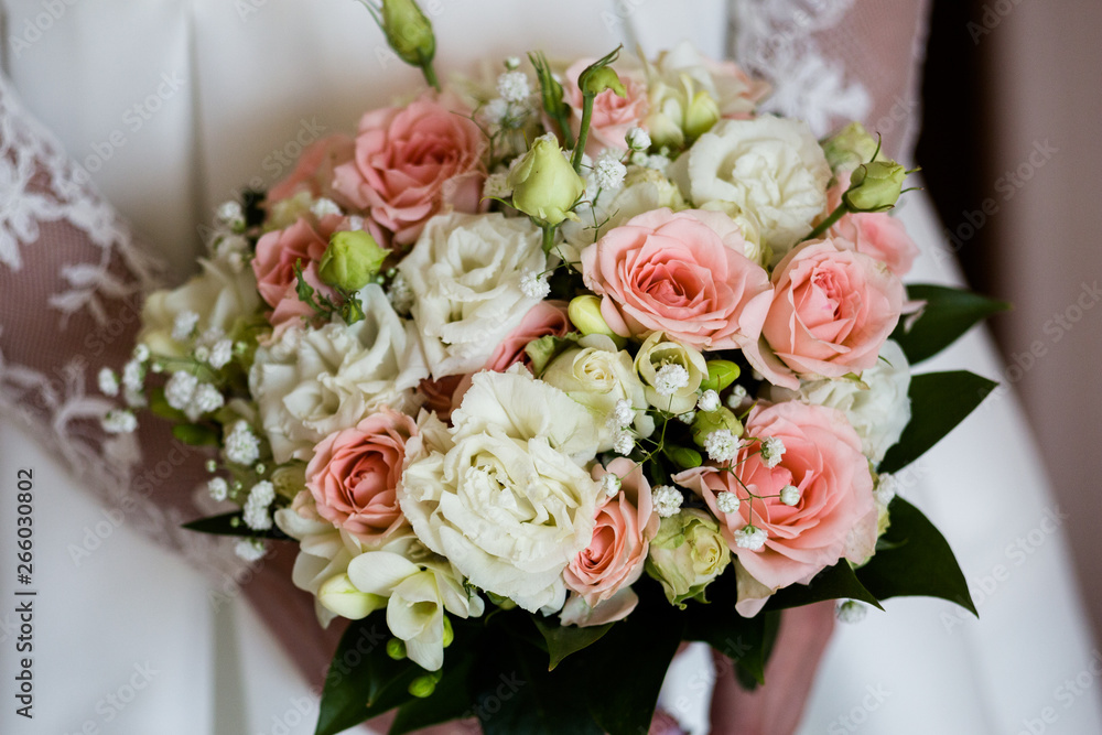 Wedding bouquet of freesia and fuchsia roses in the hands of an unrecognizable bride