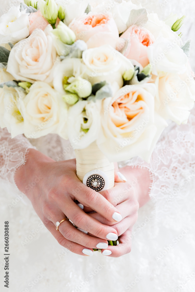 Exquisite wedding bouquet of white eustome and cream roses, in the hands of an unrecognizable bride