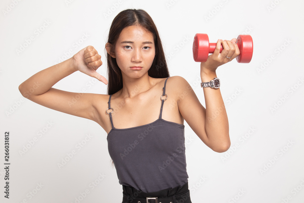 Unhappy Asian woman thumbs down with dumbbells. Unhappy Asian woman thumbs down with dumbbells.