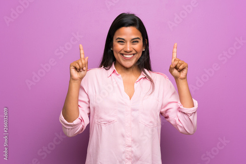 Young Colombian girl over purple wall pointing up a great idea photo