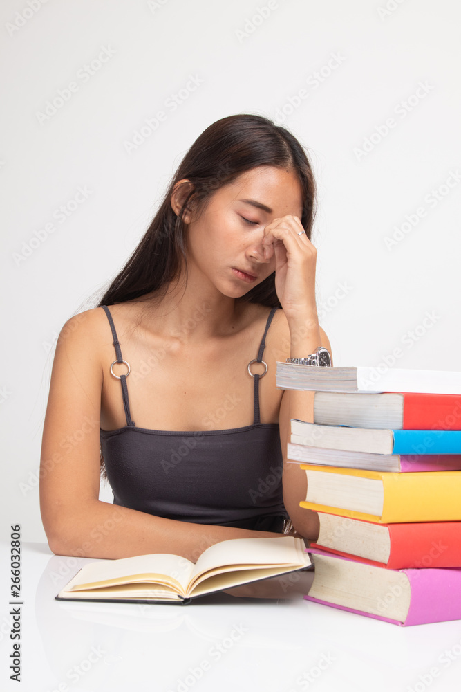 Exhausted Asian woman got headache read a book with books on table. Exhausted Asian woman got headache read a book with books on table.