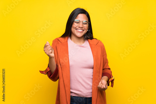 Young Colombian girl over yellow wall enjoy dancing while listening to music at a party
