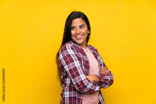 Young Colombian girl over yellow wall laughing