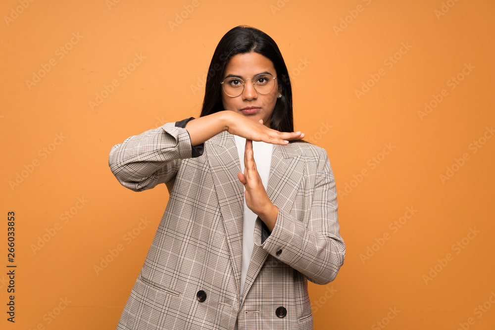 Young Colombian girl over brown wall making time out gesture Young Colombian girl over brown wall making time out gesture