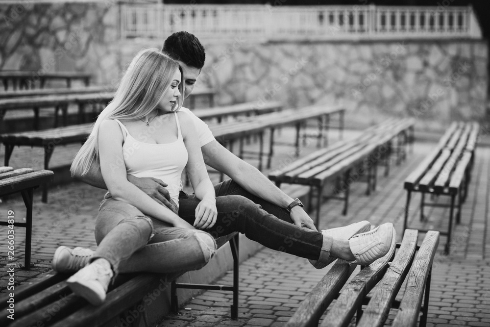 Obraz premium A young couple in love hugging on the bench in the park in black and white
