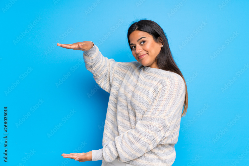 Young Colombian girl with sweater holding copyspace to insert an ad Young Colombian girl with sweater holding copyspace to insert an ad