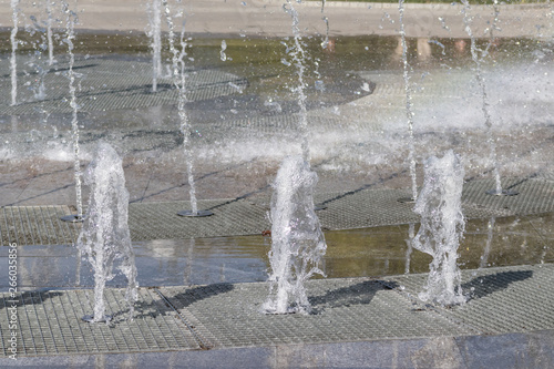 Flow splashes of water of city fountain  foam in jet of water. Fragment of recreation zone of the city park