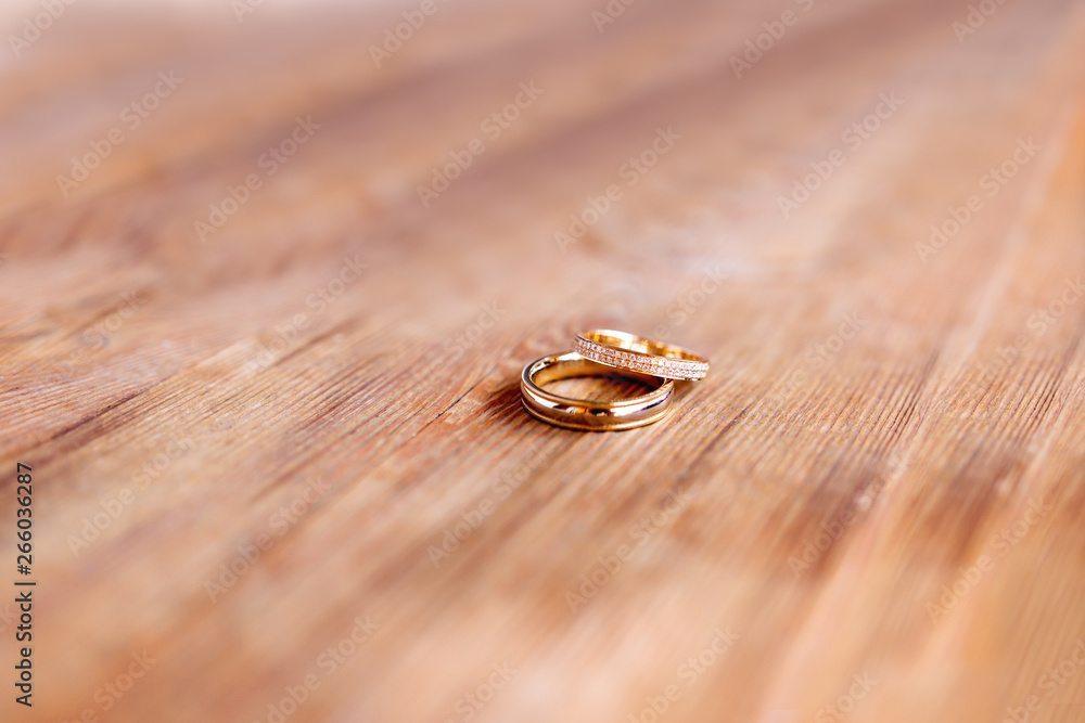 Pair of golden wedding rings with diamonds on shabby wooden background. Symbol of love, marriage and the fifth (wooden) wedding anniversary. Pair of golden wedding rings with diamonds on shabby wooden background. Symbol of love, marriage and the fifth (wooden) wedding anniversary.