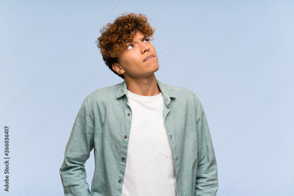 Young african american man over isolated blue wall with confuse face expression Young african american man over isolated blue wall with confuse face expression