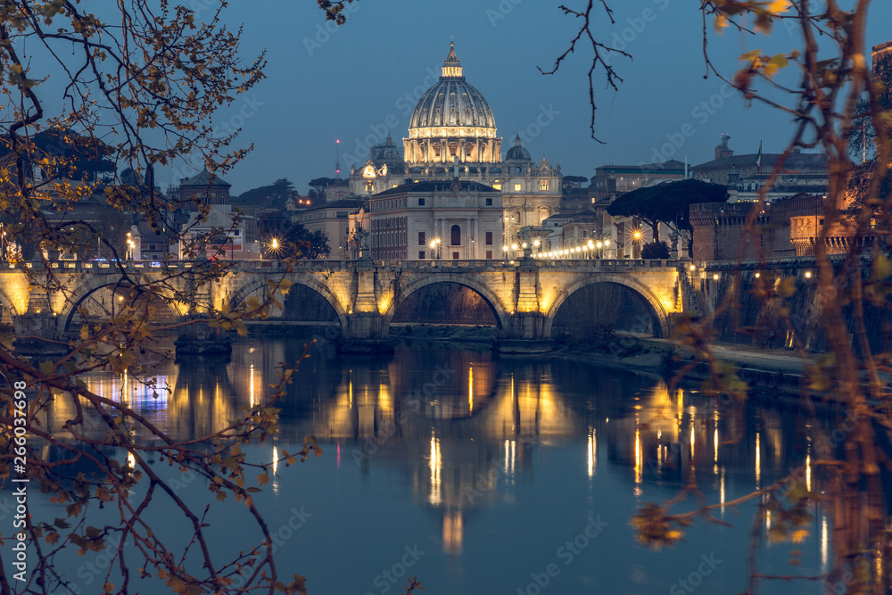 Aurelius Bridge or Ponte Sisto Bridge with St Peters Basilica and Tiber River at the blue hour with artificial lighting and reflections. Stone bridge at night over river Tiber in the historic center o