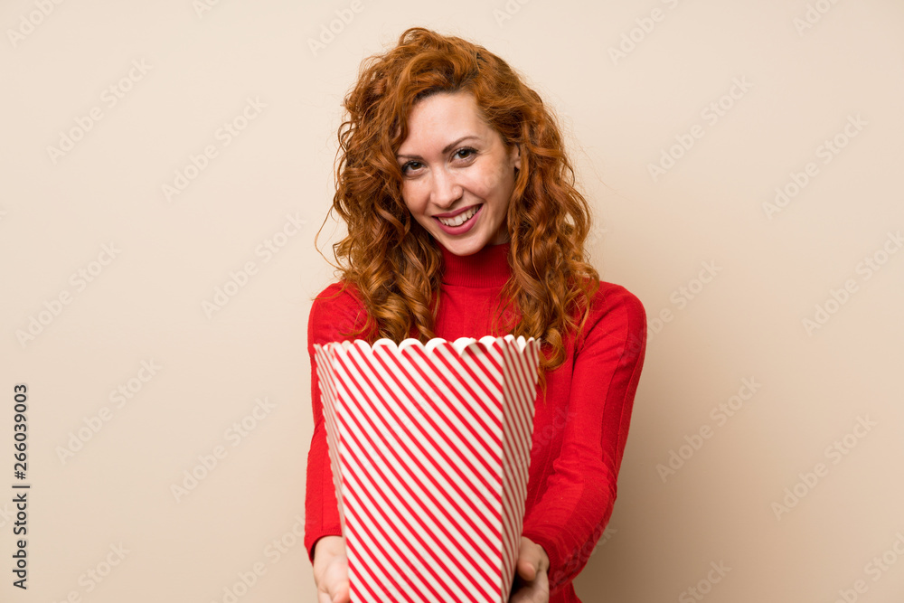 Redhead woman with turtleneck sweater holding a bowl of popcorns Redhead woman with turtleneck sweater holding a bowl of popcorns