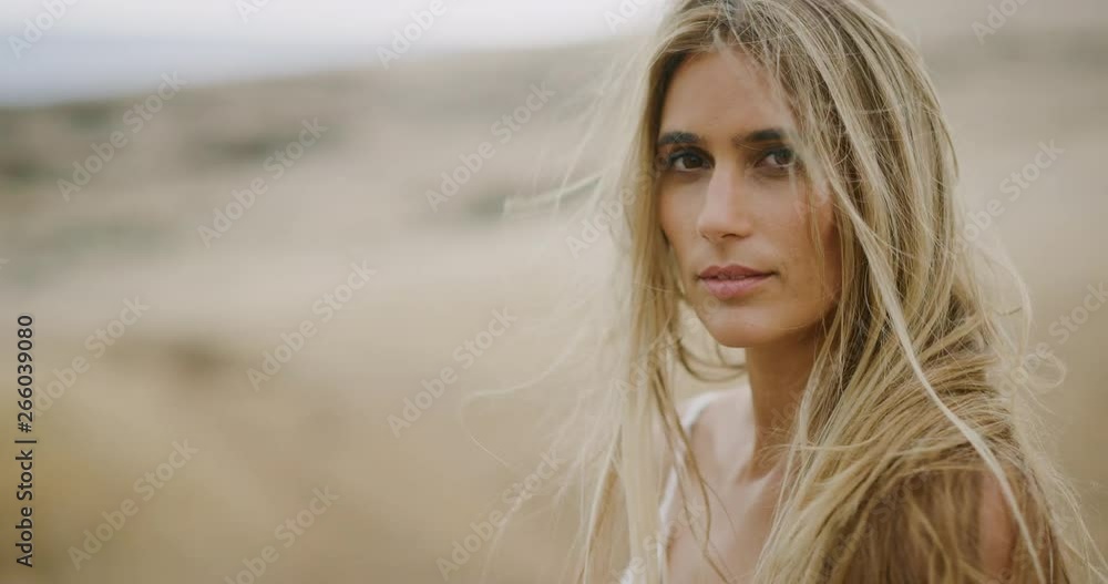 Portrait of beautiful young woman looking into the camera with her hair blowing in the wind in slow motion, bohemian bride lifestyle Portrait of beautiful young woman looking into the camera with her hair blowing in the wind in slow motion, bohemian bride lifestyle