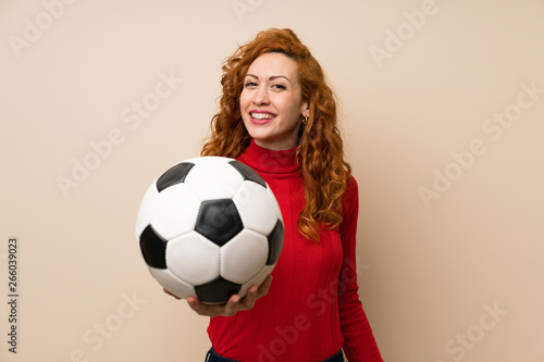 Redhead woman with turtleneck sweater holding a soccer ball © luismolinero