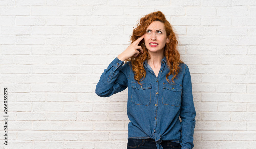 Redhead woman over white brick wall with problems making suicide gesture Redhead woman over white brick wall with problems making suicide gesture
